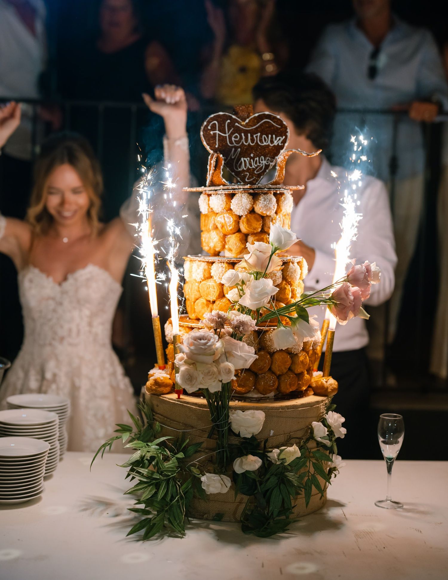 Elegant wedding dessert table with sparklers and floral decorations on white tablecloth.