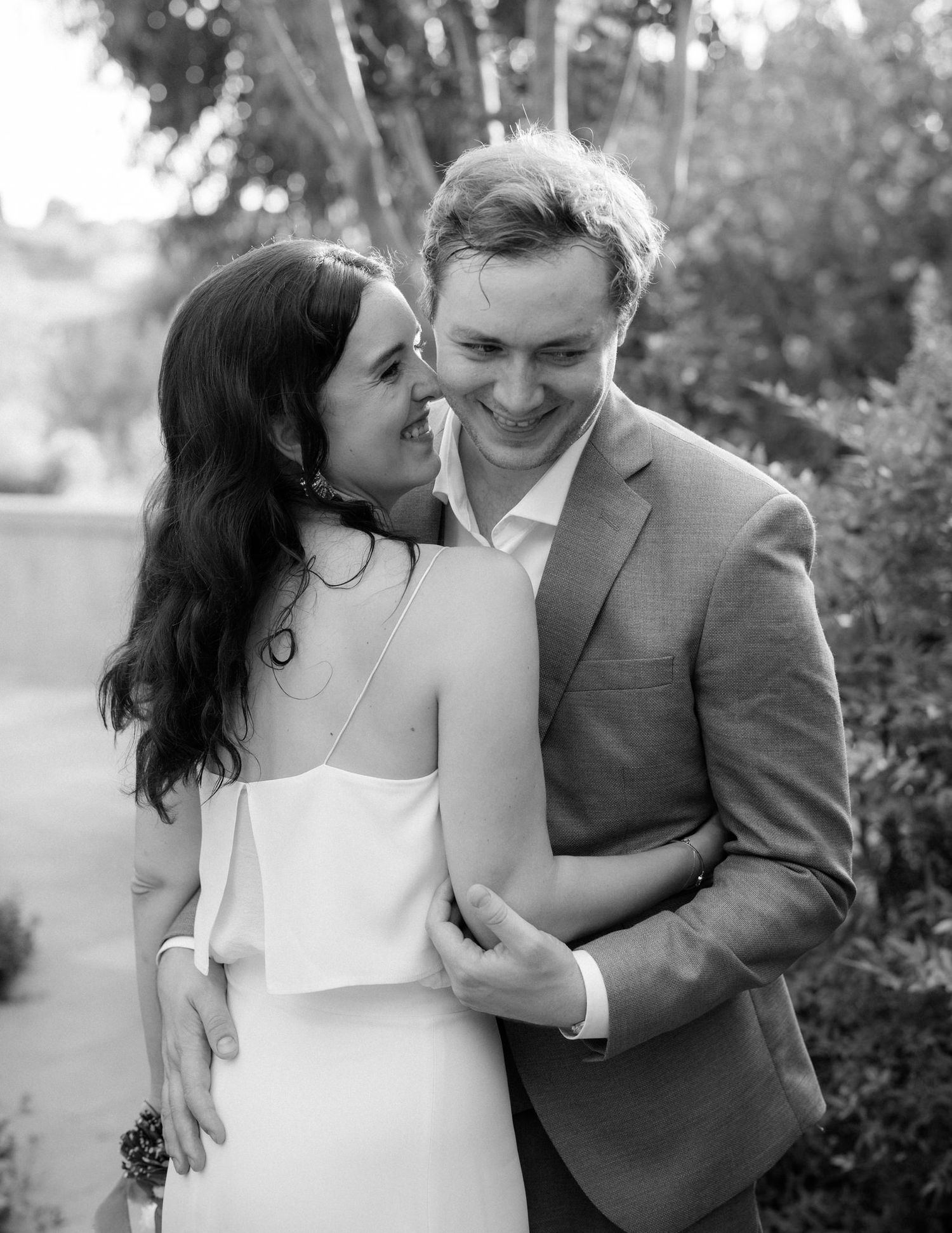 Intimate black and white portrait of newlyweds sharing tender moment outdoors.
