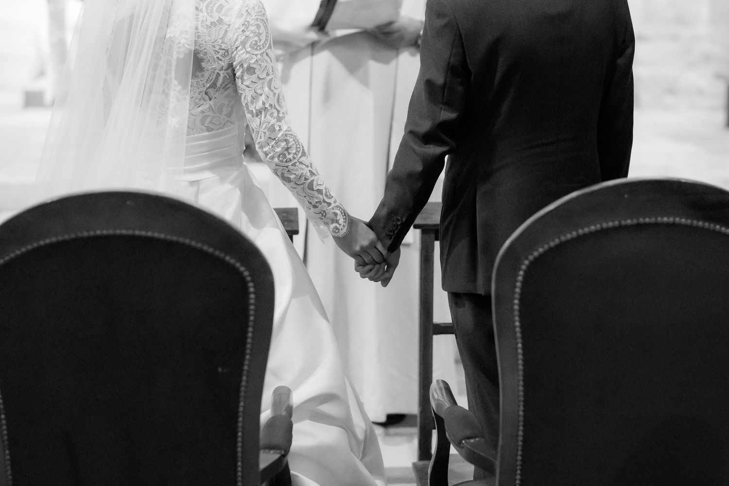 Black and white photo of a couple during their wedding ceremony in a church interior.