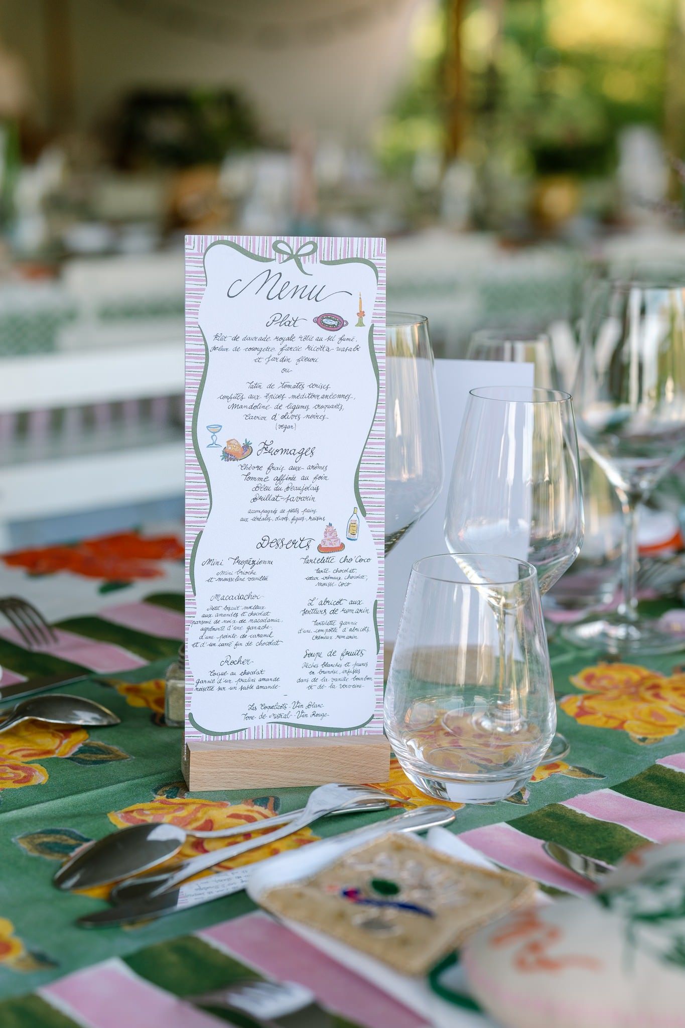 Elegant table settings with menu cards and wine glasses on floral patterned tablecloths.