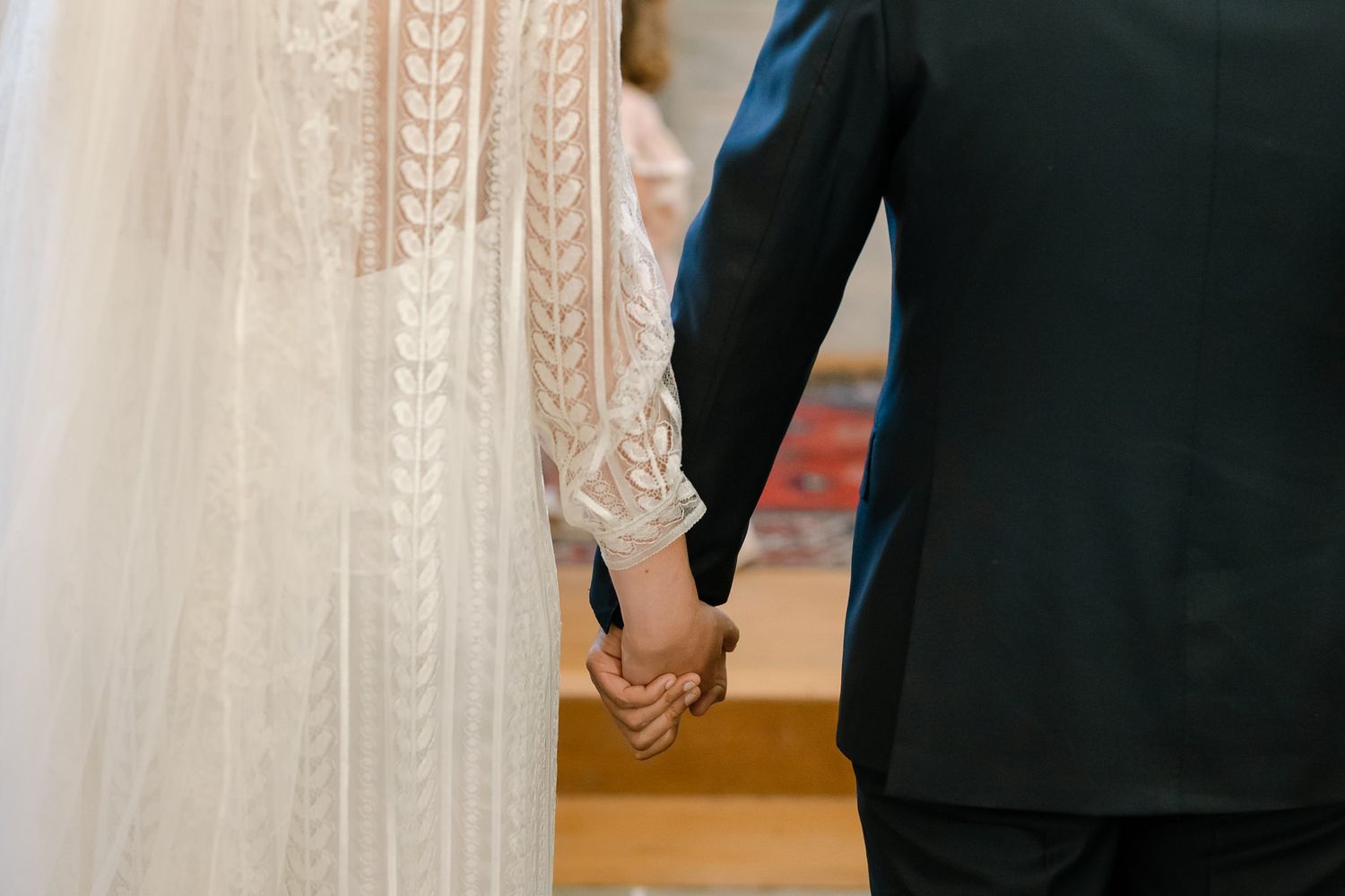 Close-up details of a white lace wedding dress during church ceremony.
