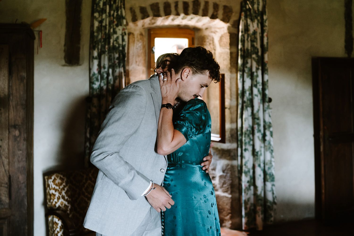 Emotional embrace captured in teal and grey tones during wedding preparations.