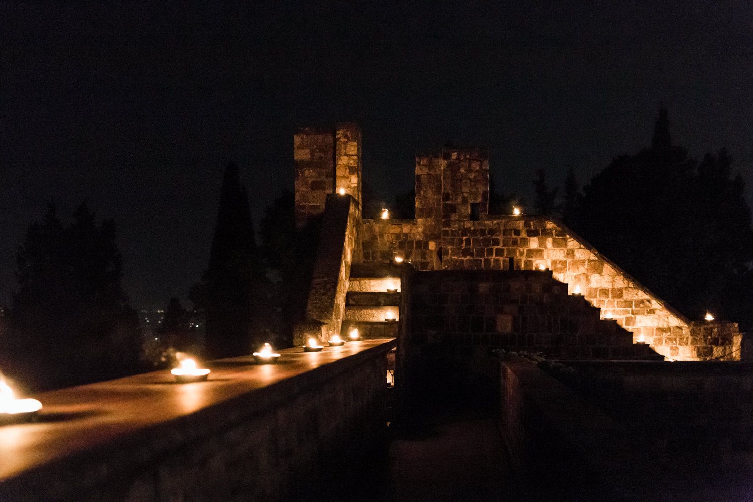 Nighttime exterior view of an illuminated castle or historic venue with glowing windows.