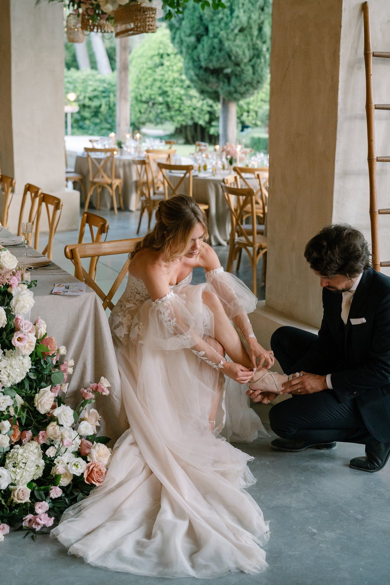 Black and white photo of elegant bridal shoes being fastened with delicate straps.