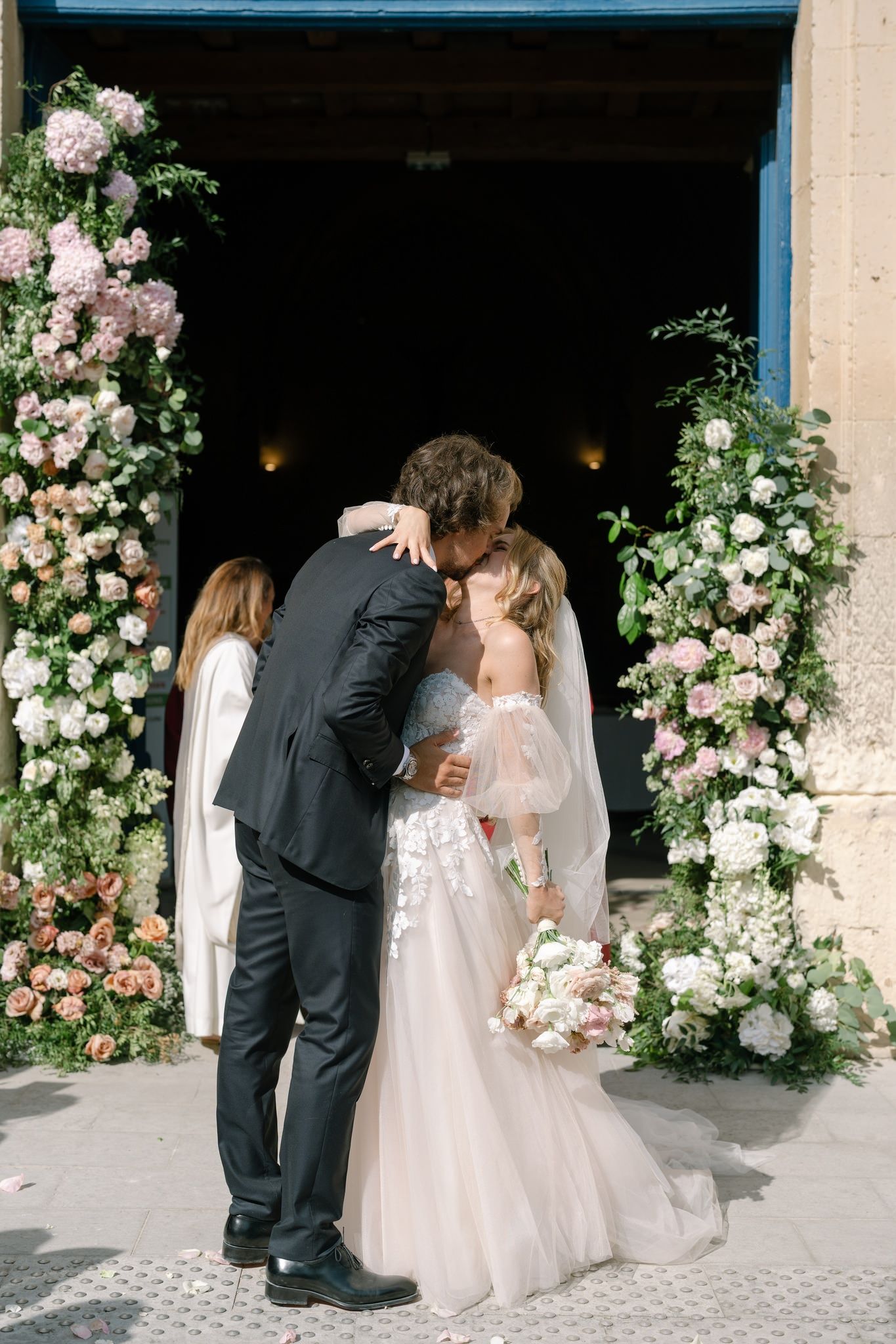 Romantic wedding moment under stone archway decorated with pink and white roses.