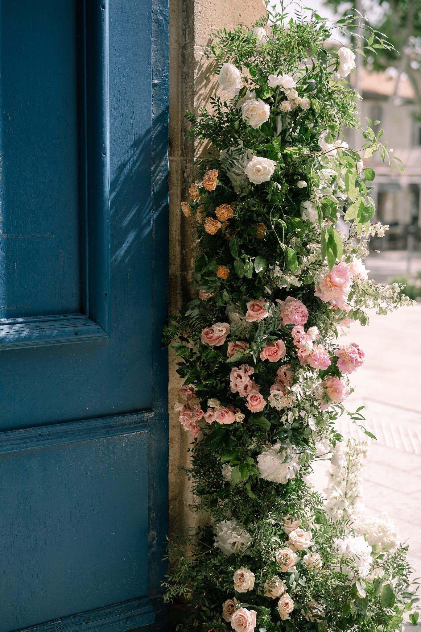 Climbing pink and peach roses adorning a blue door frame creating a romantic garden entrance.