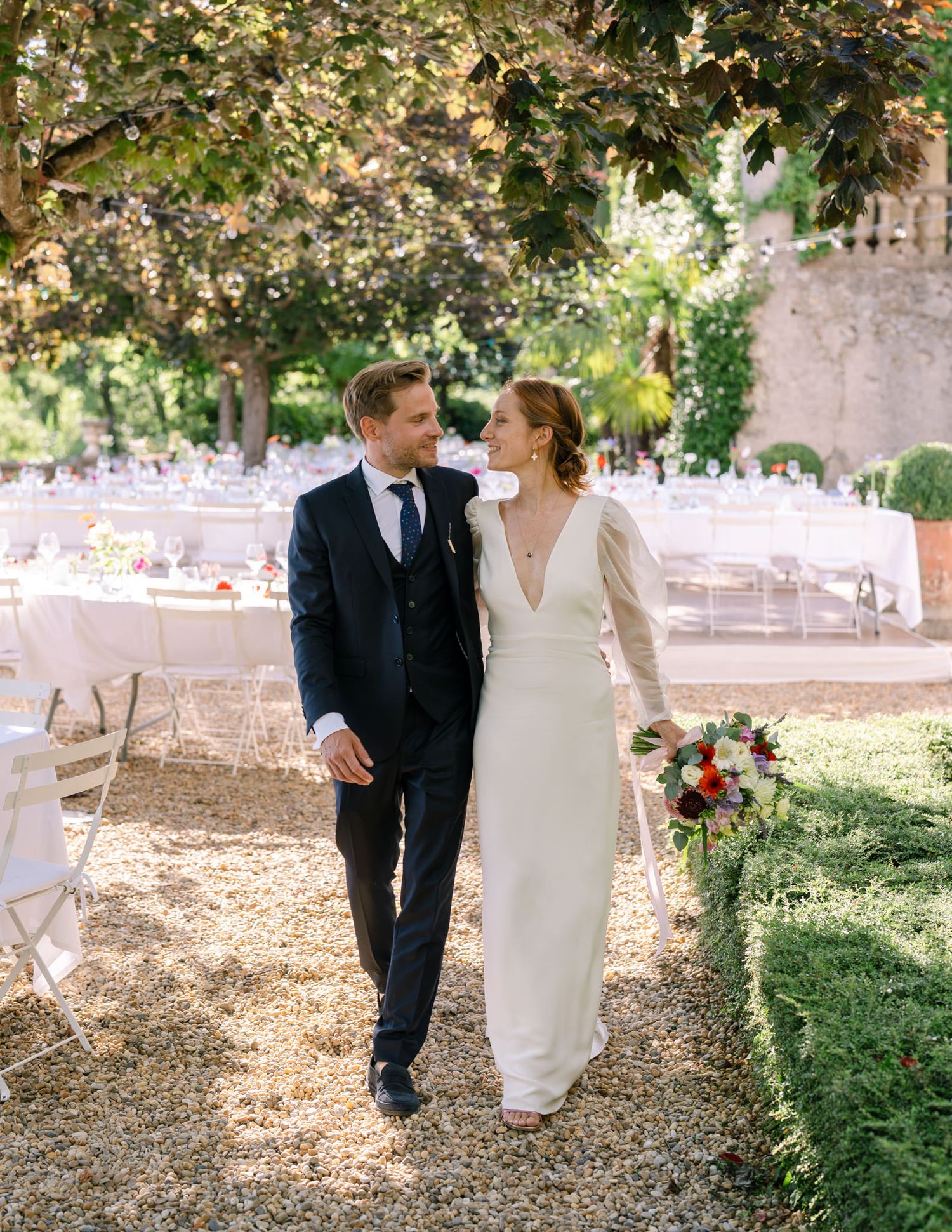 Sunlit garden wedding scene with dappled light filtering through tree canopy.