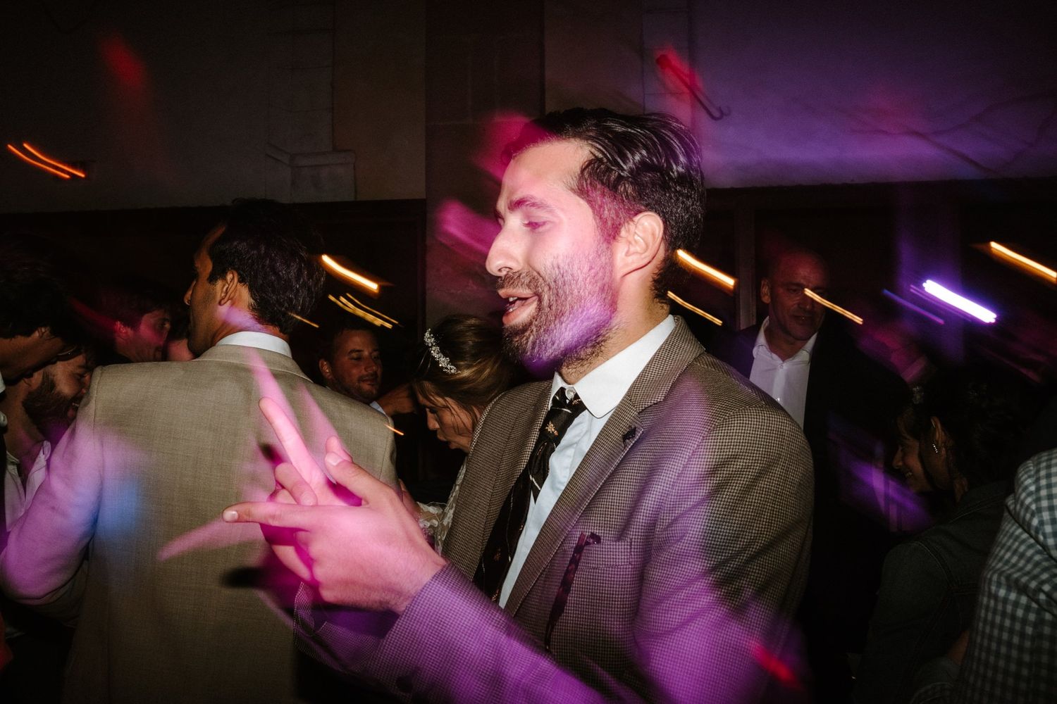 Dance floor illuminated with purple and red lighting during evening wedding celebration.