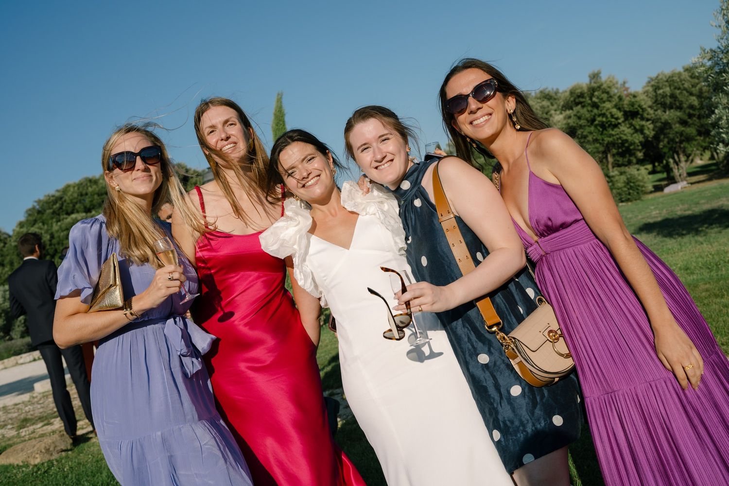 Wedding party members in colorful attire posing together outdoors.