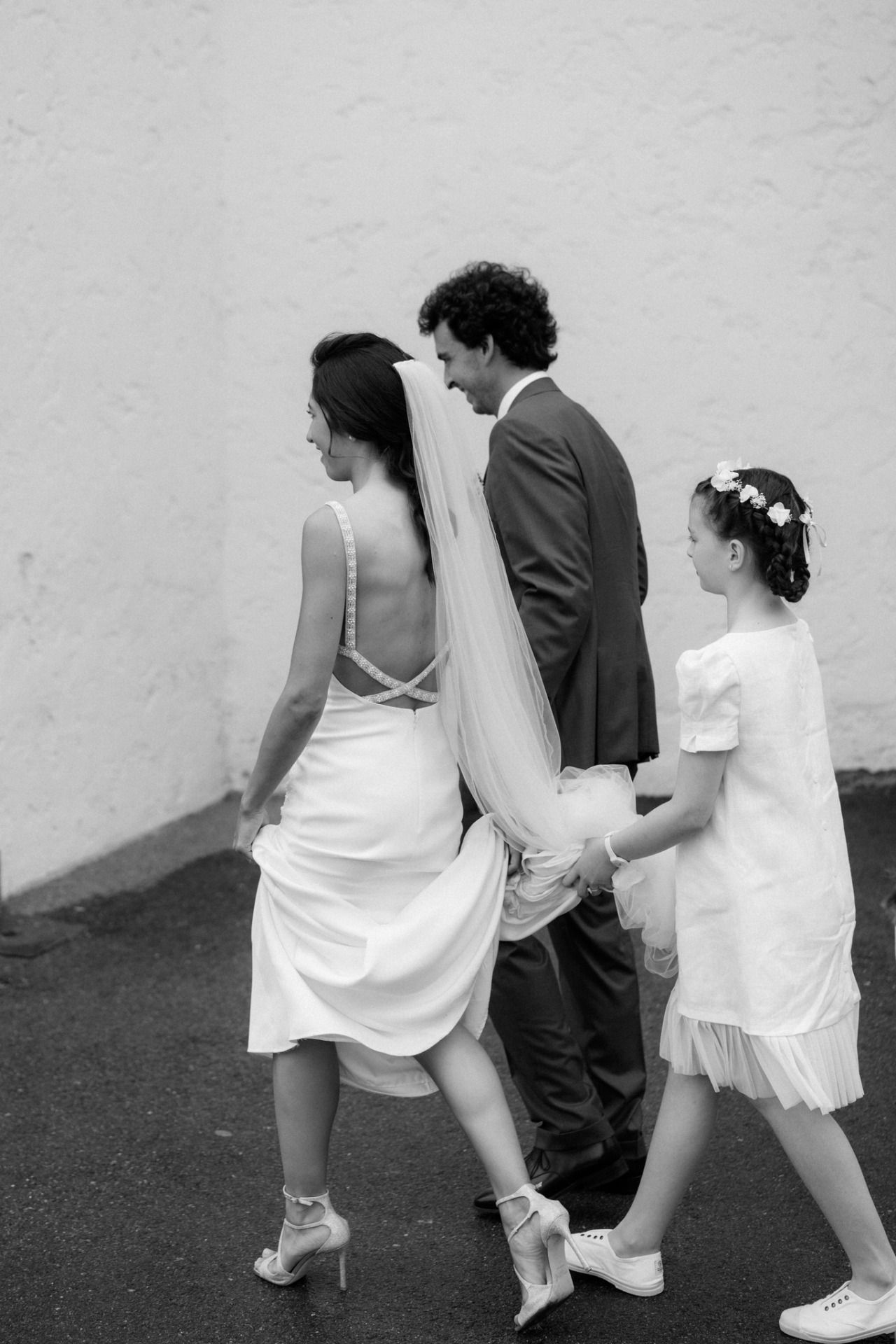 Wedding party wearing white dresses and sneakers walking together.