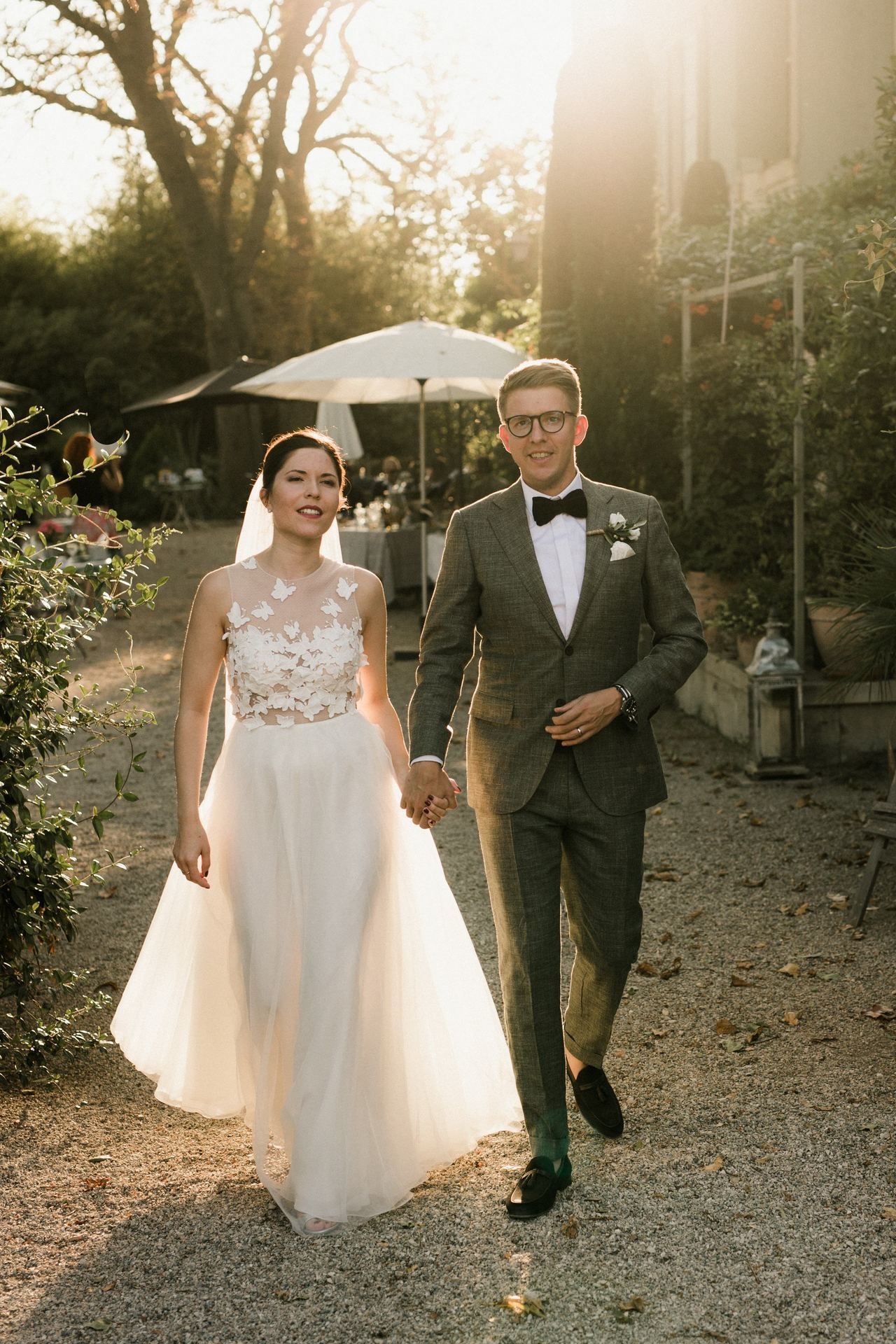 Wedding couple walking together on a gravel path during golden hour.