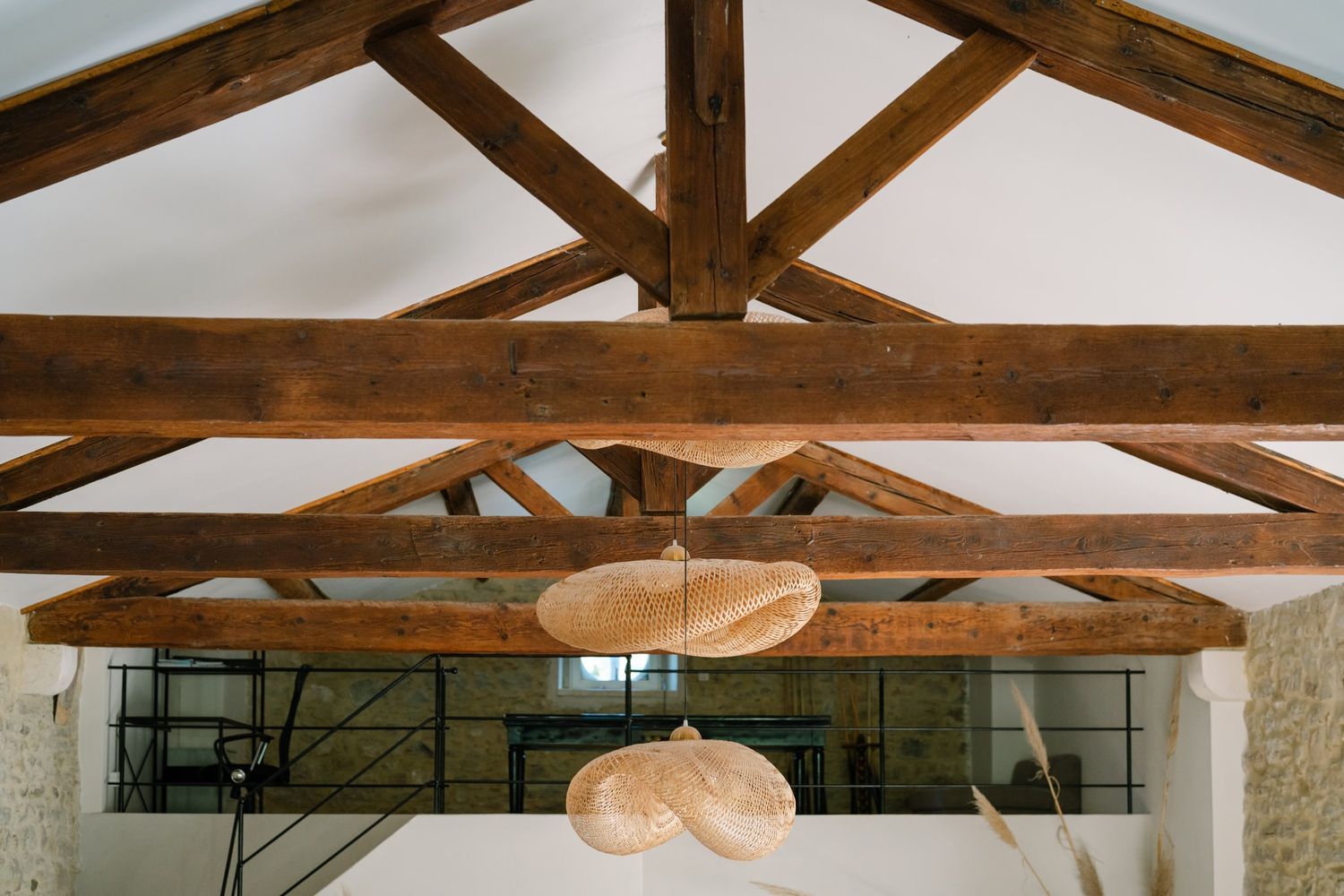 Interior view of exposed wooden beam ceiling with pendant lights in rustic style.