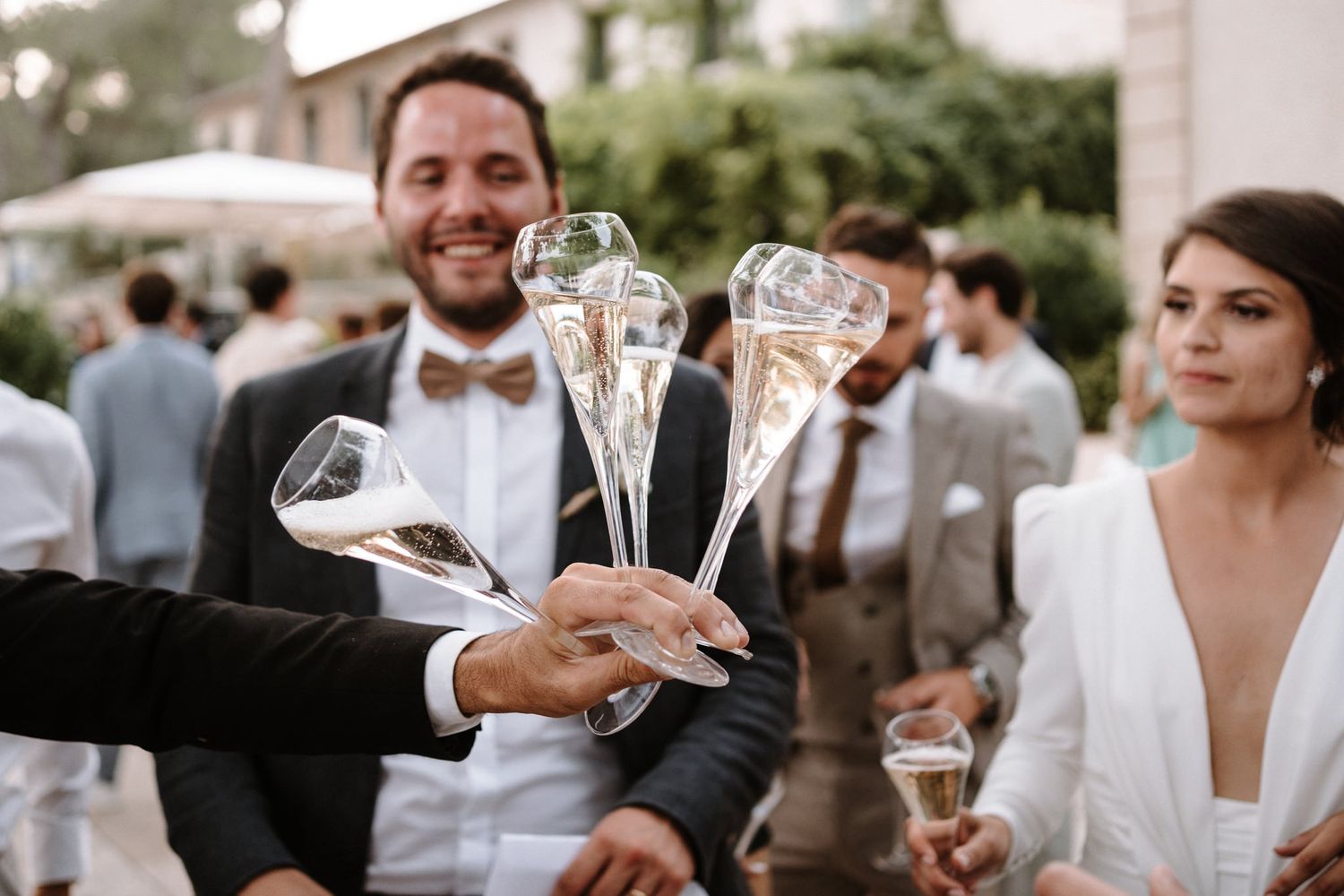 Wedding guests holding champagne flutes at an outdoor reception celebration.