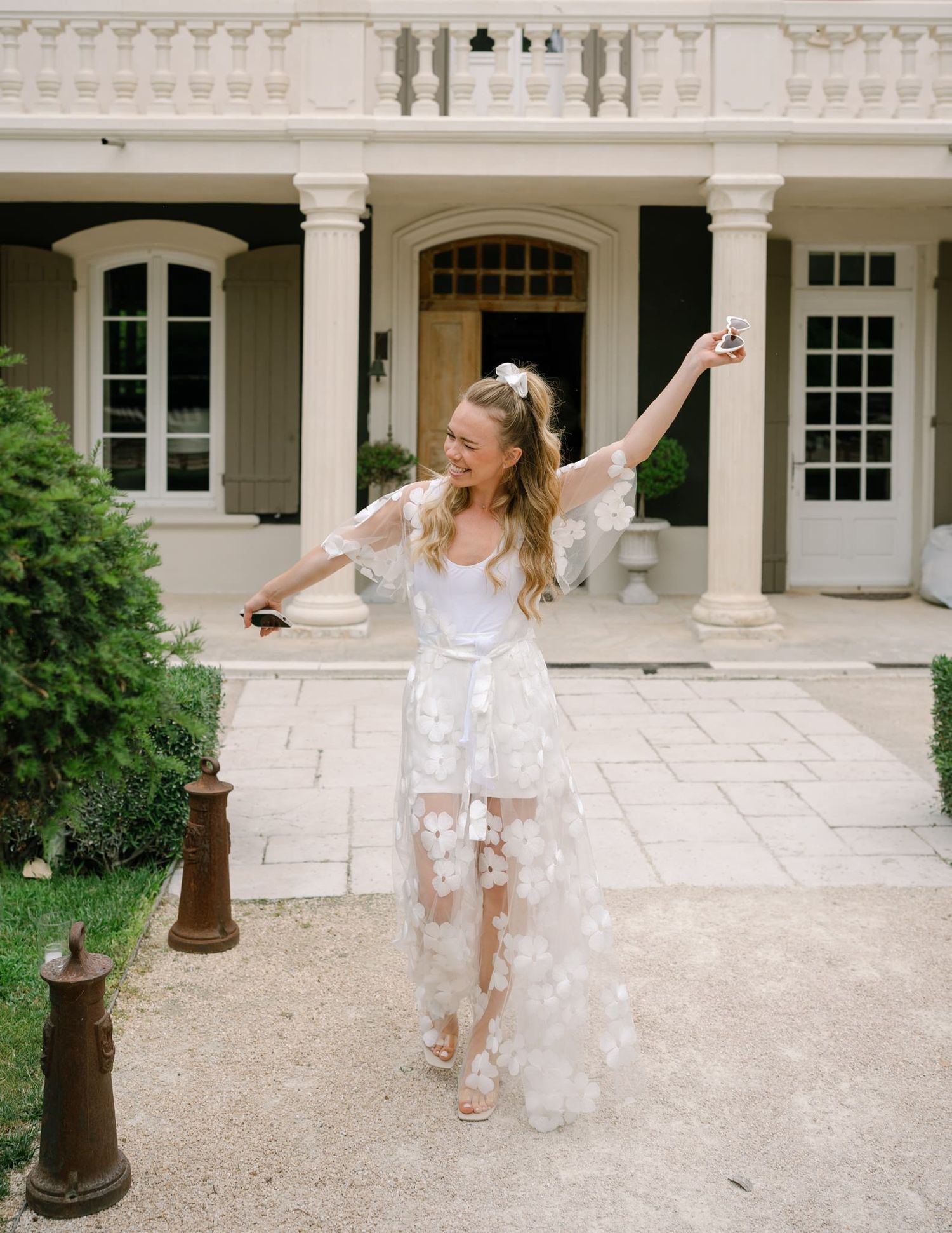 Person in white dress twirling joyfully on a grand estate patio.