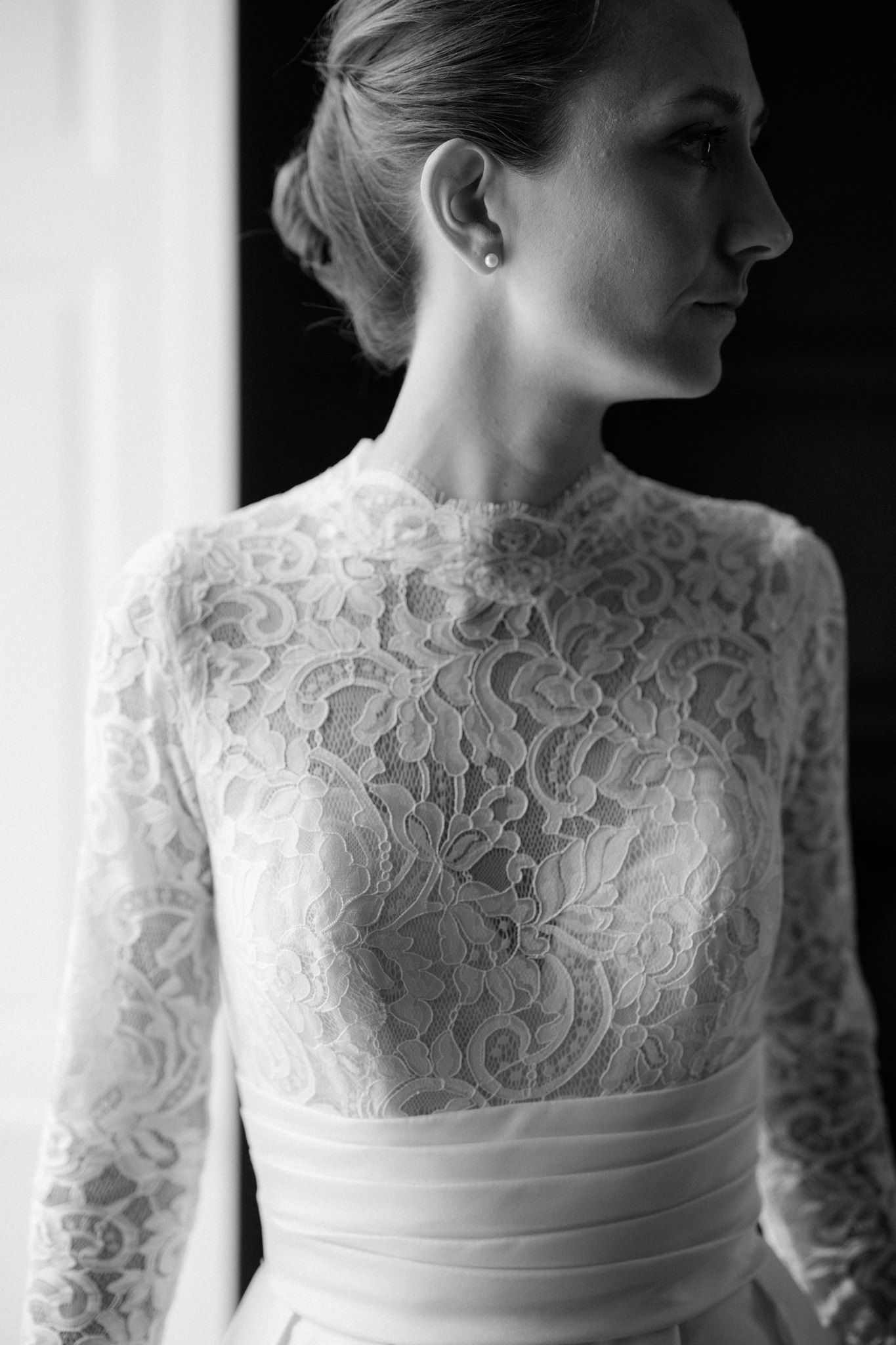 Close-up details of an elegant lace wedding dress bodice with long sleeves in black and white.