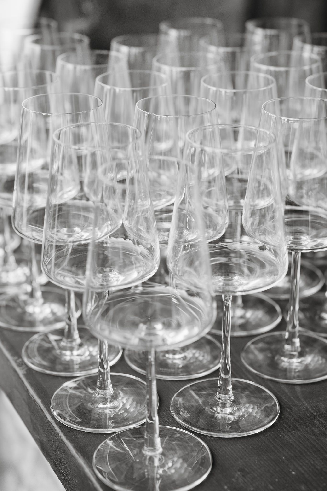 Empty wine glasses arranged in rows on a dark surface for an elegant event.