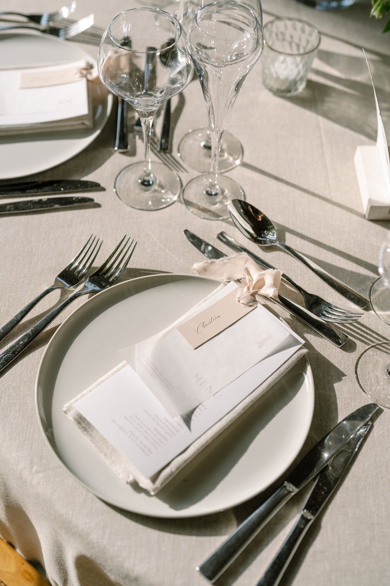 Elegant table settings with white plates, crystal glasses and formal silverware arrangements.