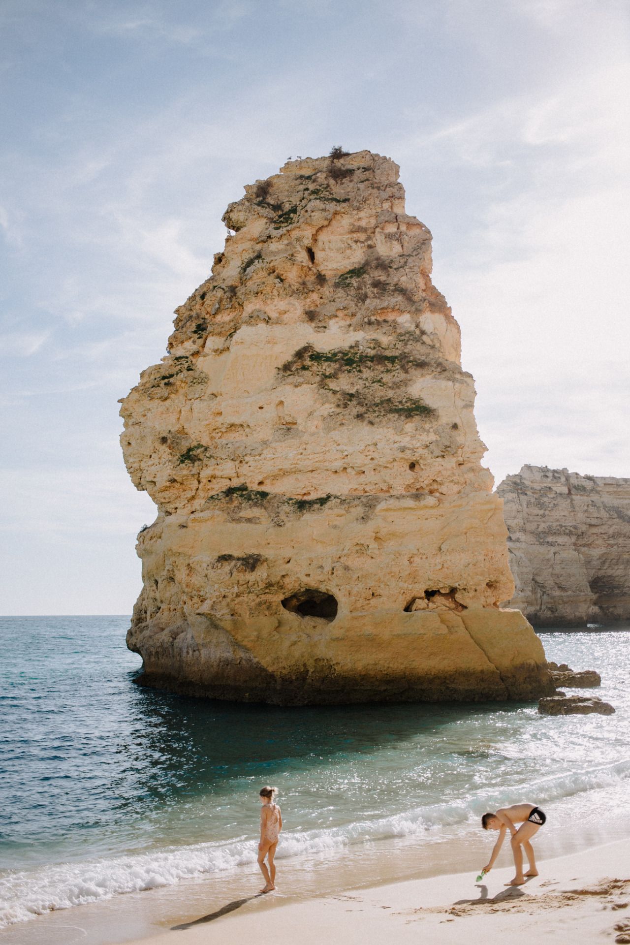 Dramatic limestone cliffs and rock formations tower over a pristine beach in Portugal.