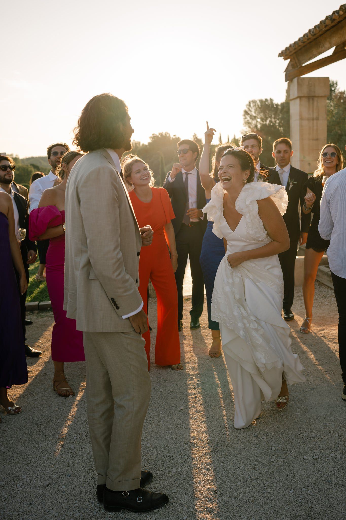 Joyful laughter and dancing at sunset during outdoor wedding reception.