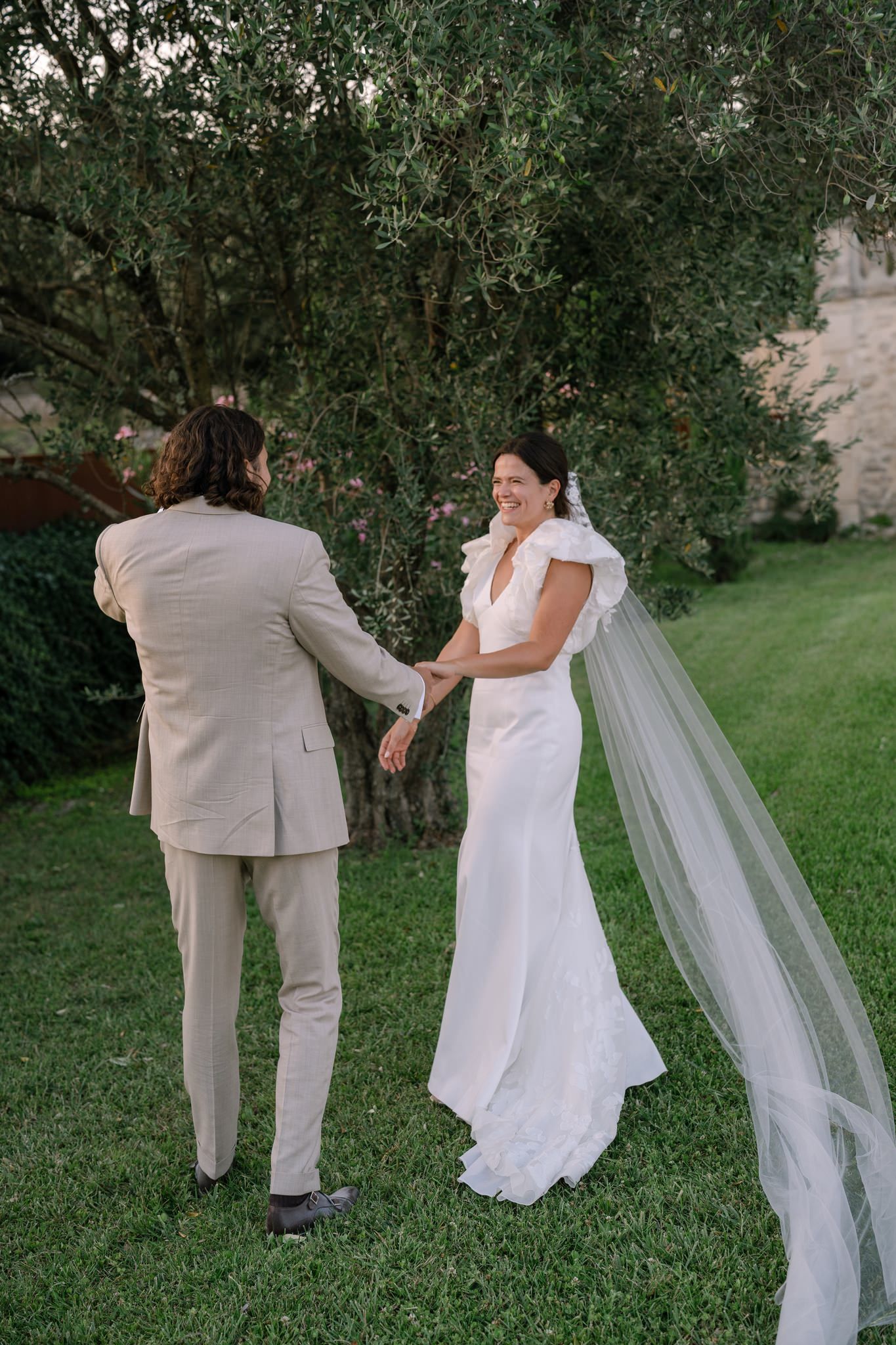 Intimate moment between newlyweds with flowing veil in garden setting.