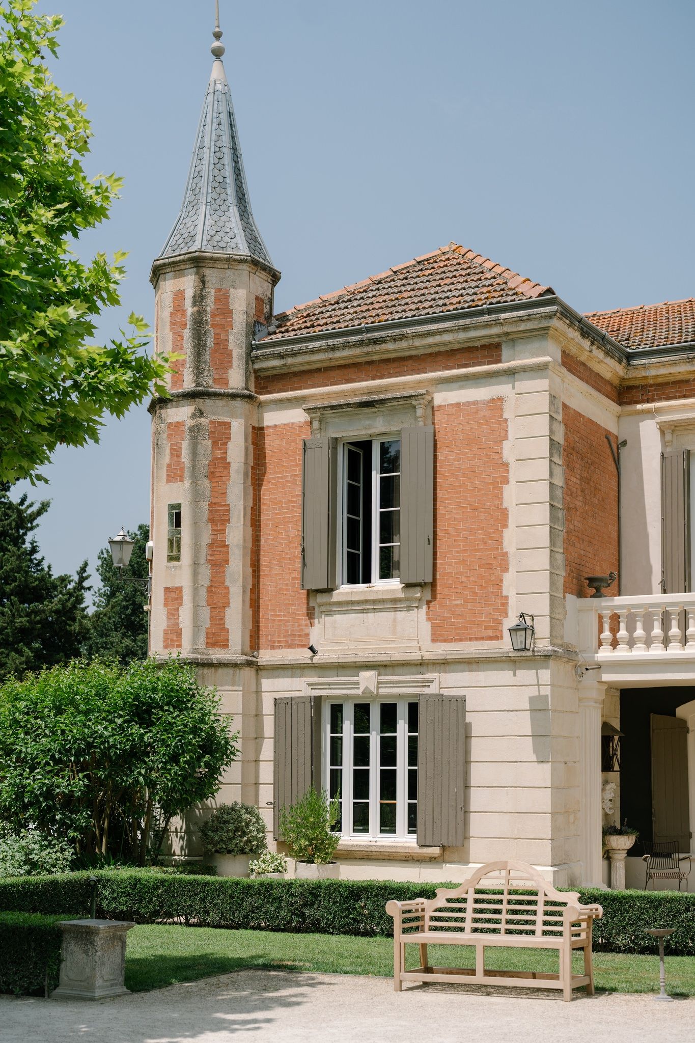 Elegant French chateau-style building with brick walls and stone trim under blue sky.