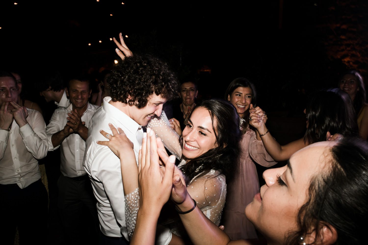 Energetic dance floor scene with party guests celebrating under dim lighting.