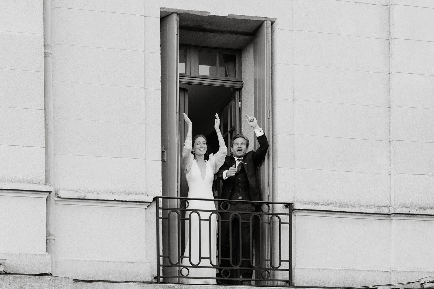 Wedding celebration viewed through multiple windows of a white building facade.