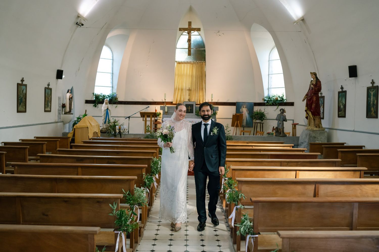 Church interior with wooden pews and arched ceiling decorated for wedding ceremony.