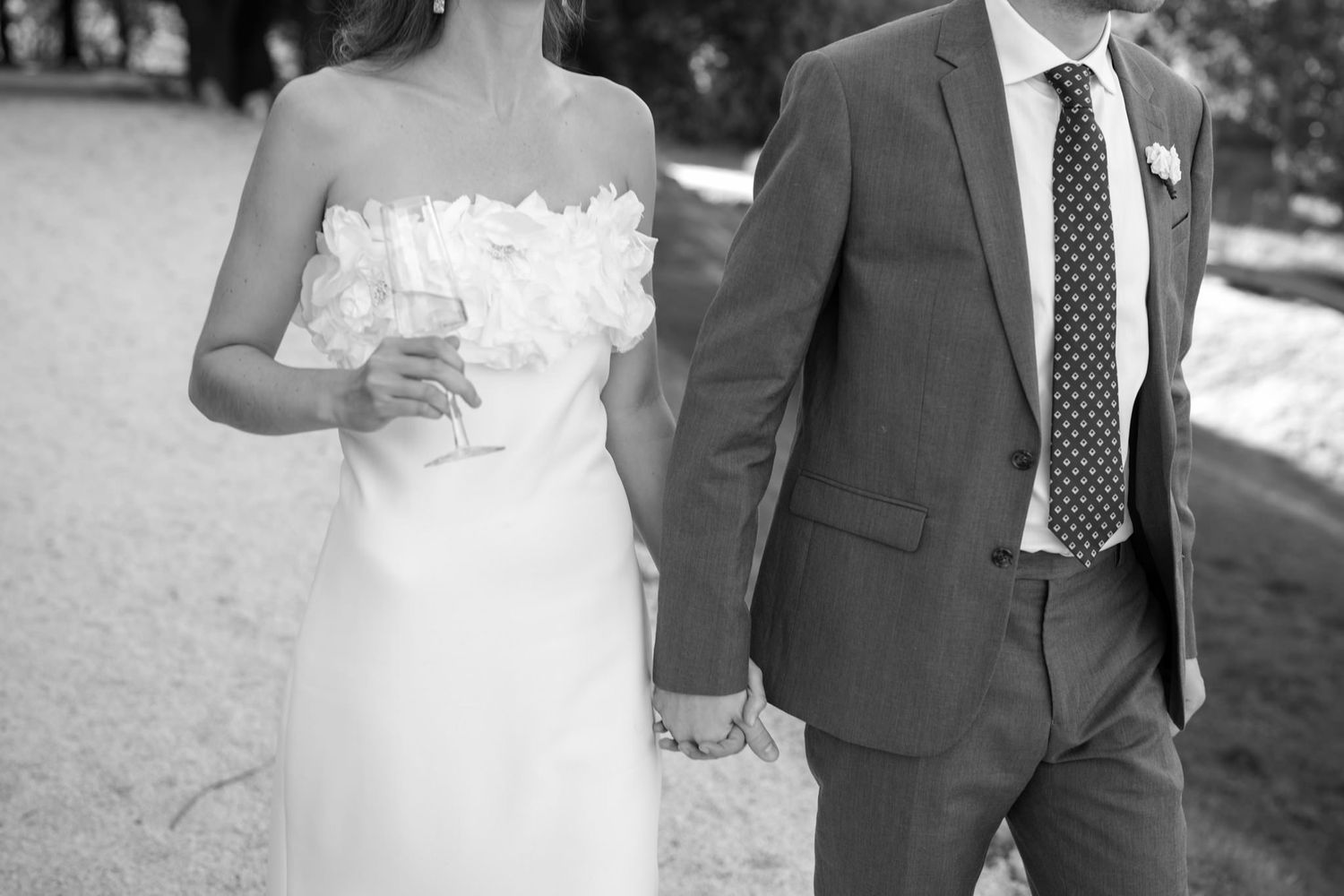 A couple strolling side by side in wedding attire on a sunny day.