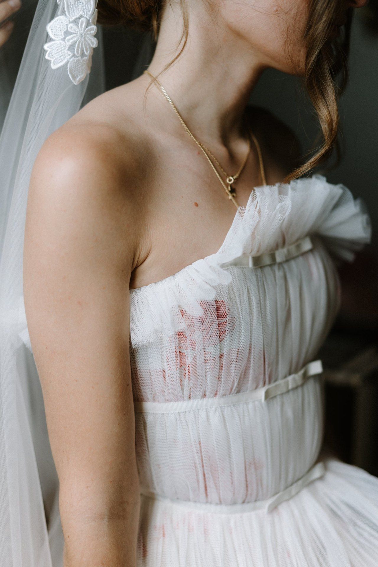 Close-up details of a white wedding dress bodice with delicate fabric and pleating.