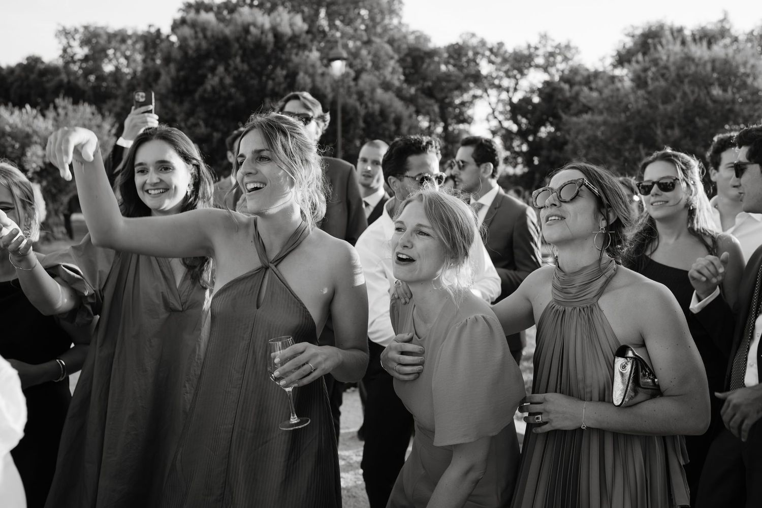 Black and white candid shot of wedding guests during outdoor celebration.