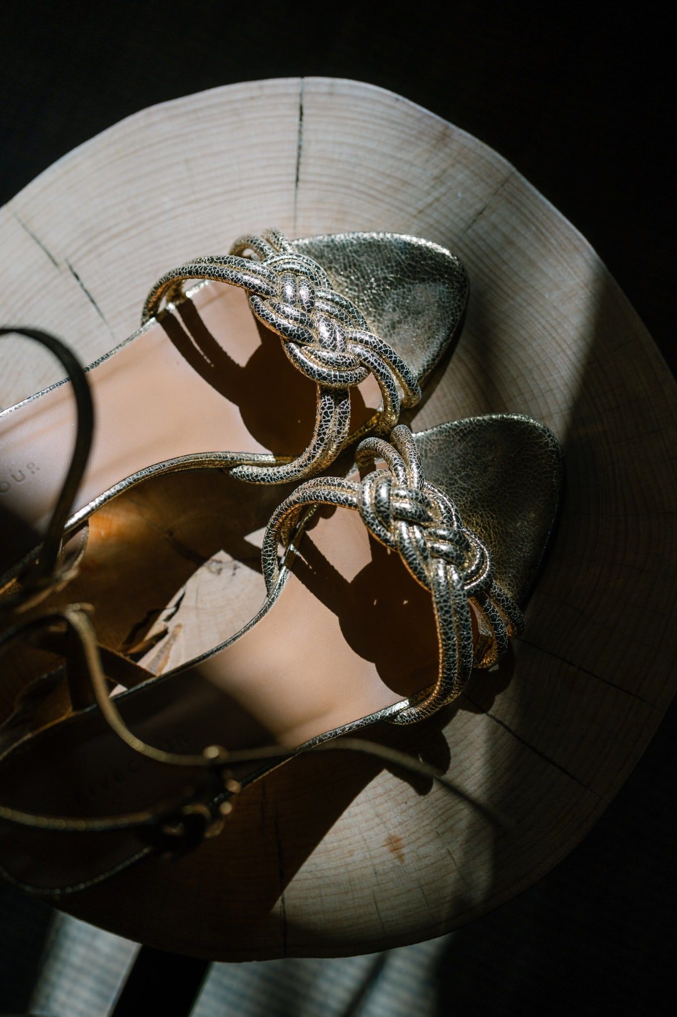 Elegant silver bridal shoes photographed in dramatic lighting.