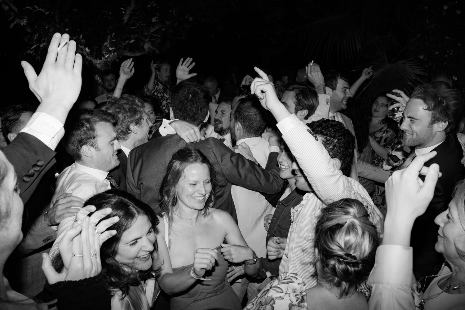 Energetic crowd with raised hands dancing at a lively party celebration.