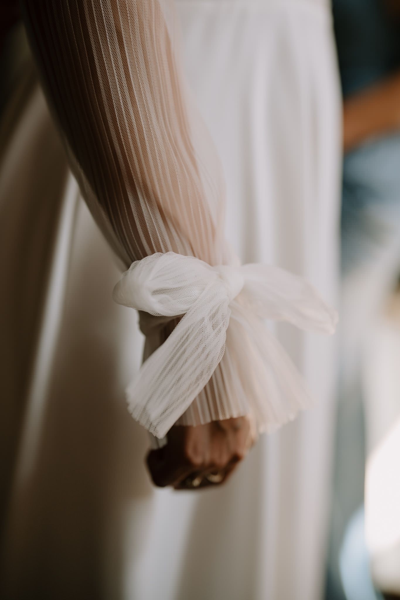 Close-up detail of delicate white tulle sleeve cuff on a wedding dress.