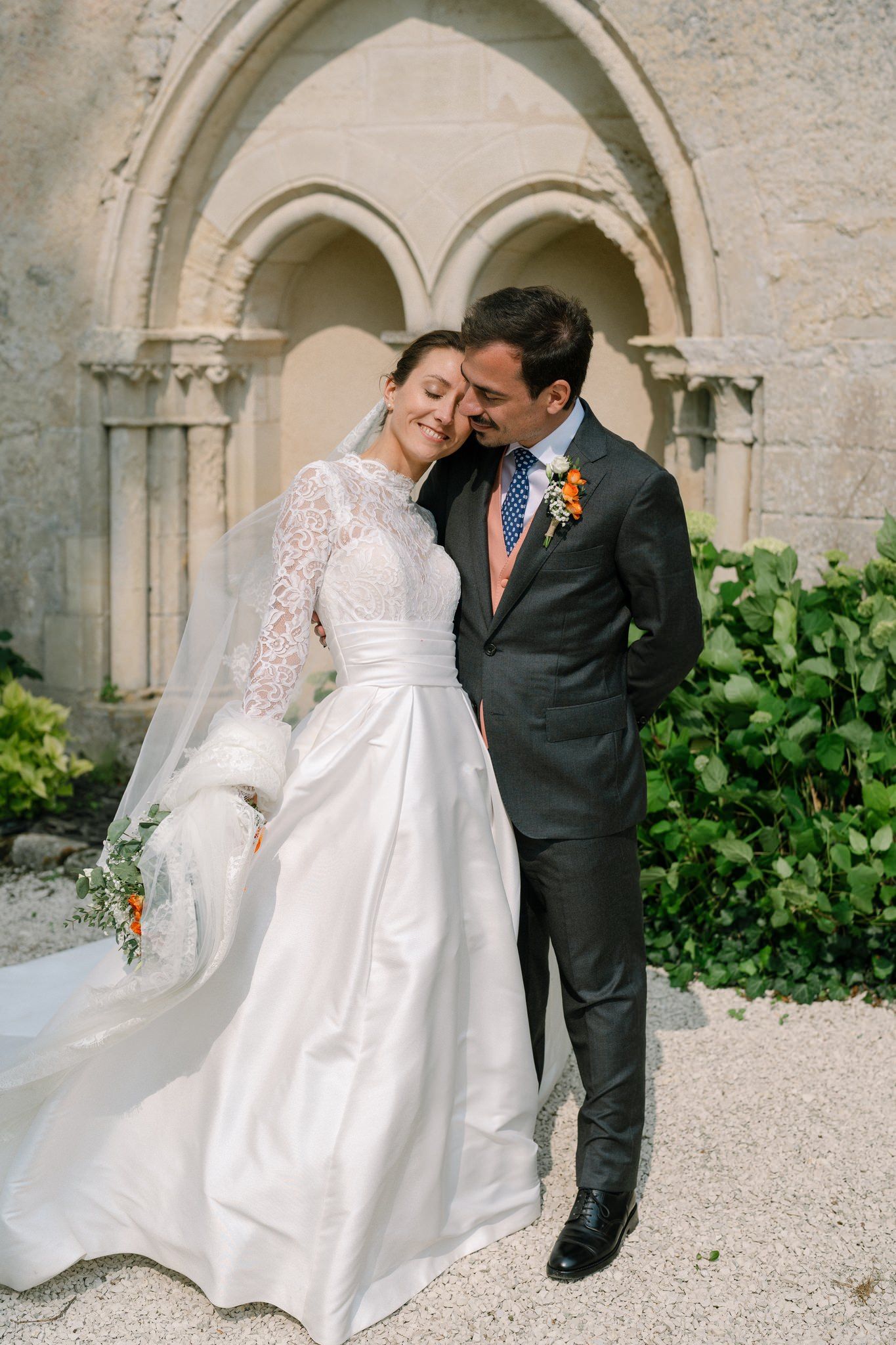 Wedding couple posing under stone archways at a French chateau.