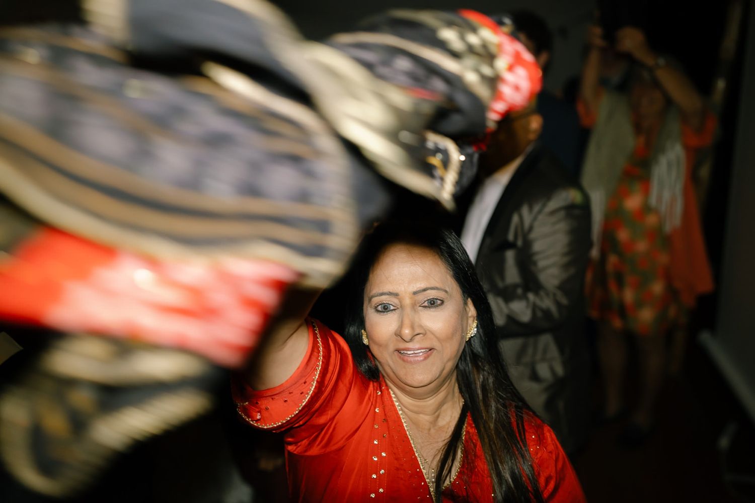 Wedding guests dancing and celebrating with traditional decorative accessories at night.