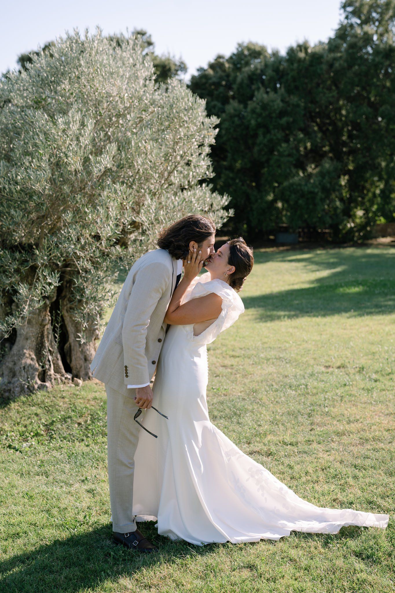 Romantic wedding moment captured in an olive grove with flowing white dress.
