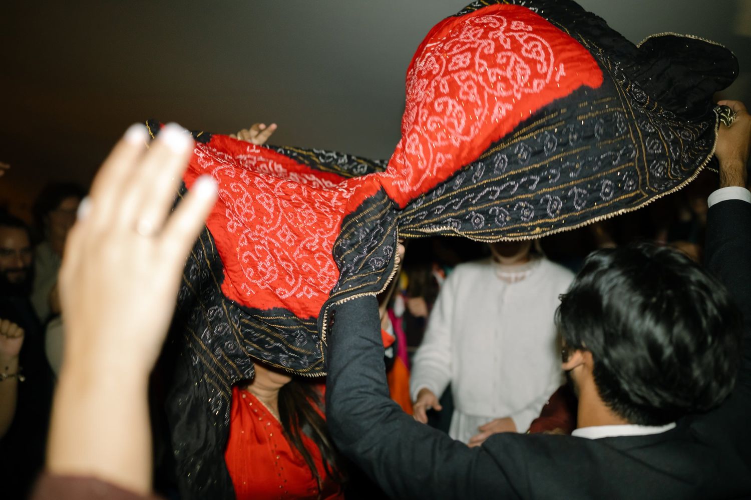 A decorative red and black hat being passed around during festive wedding celebrations.