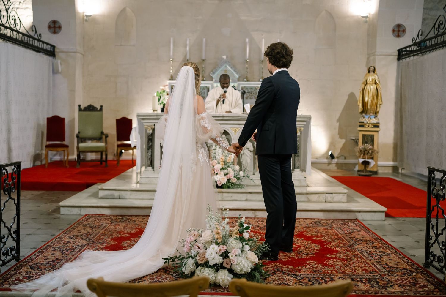 Church wedding ceremony with elegant decor and red carpet leading to ornate altar.
