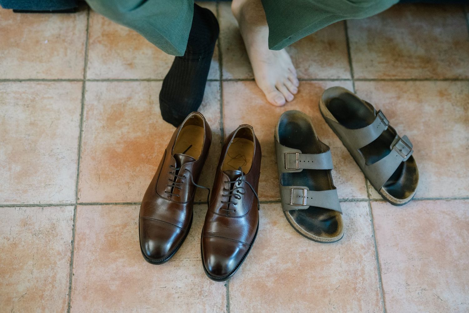 Wedding guests' formal shoes lined up on a tiled floor.