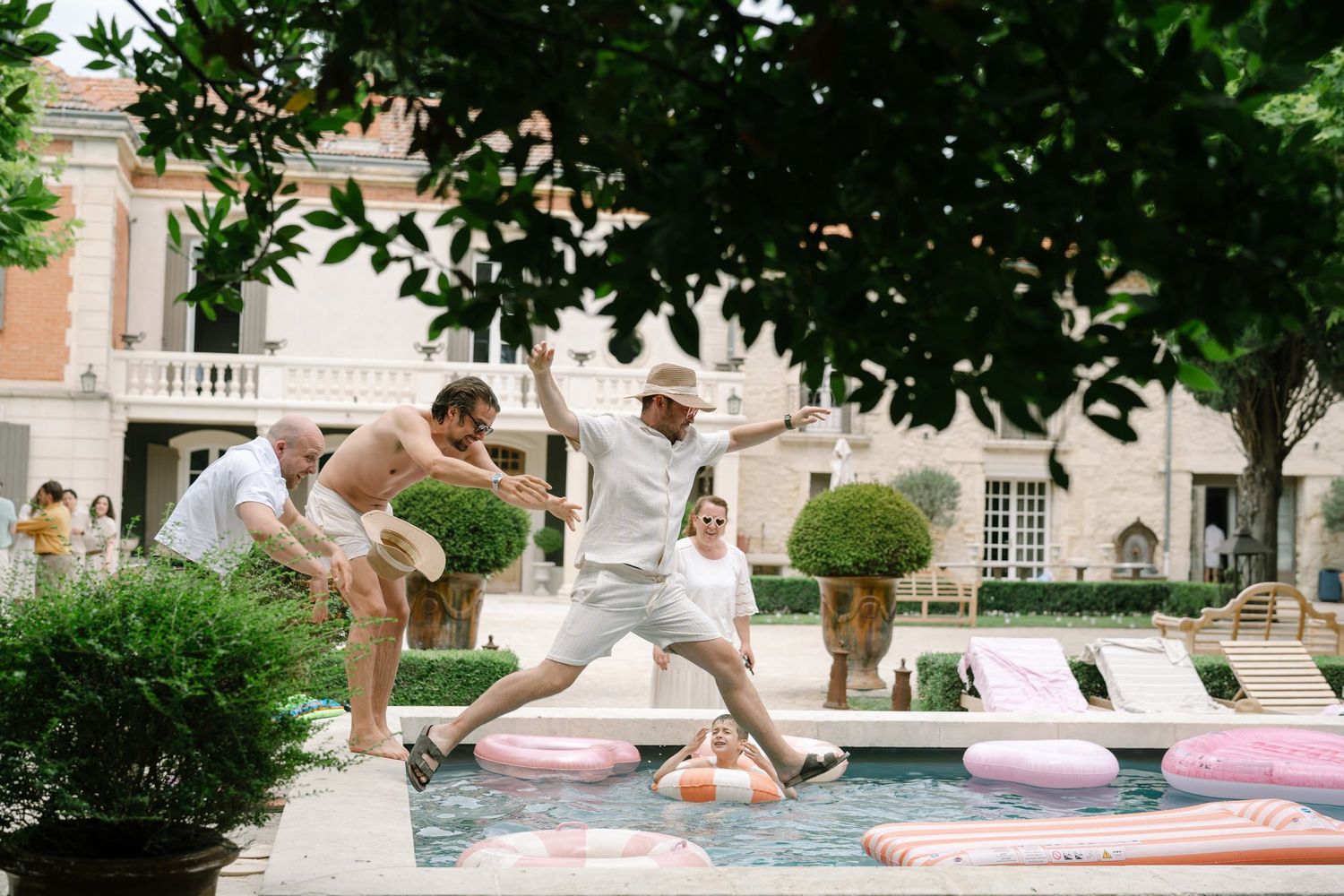 Friends jumping into a swimming pool during a summer celebration.