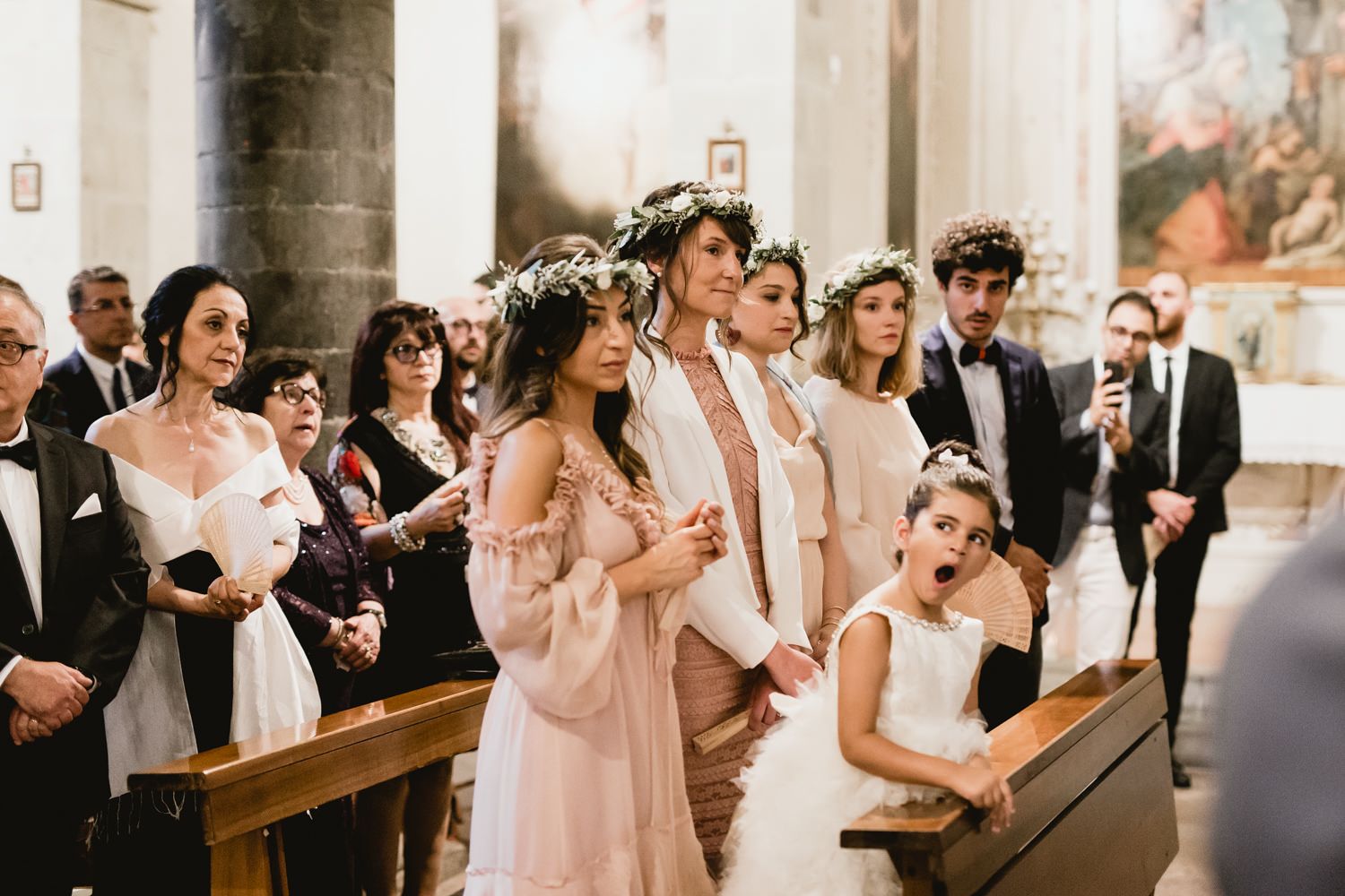 Wedding ceremony taking place in a traditional church with guests seated in wooden pews.