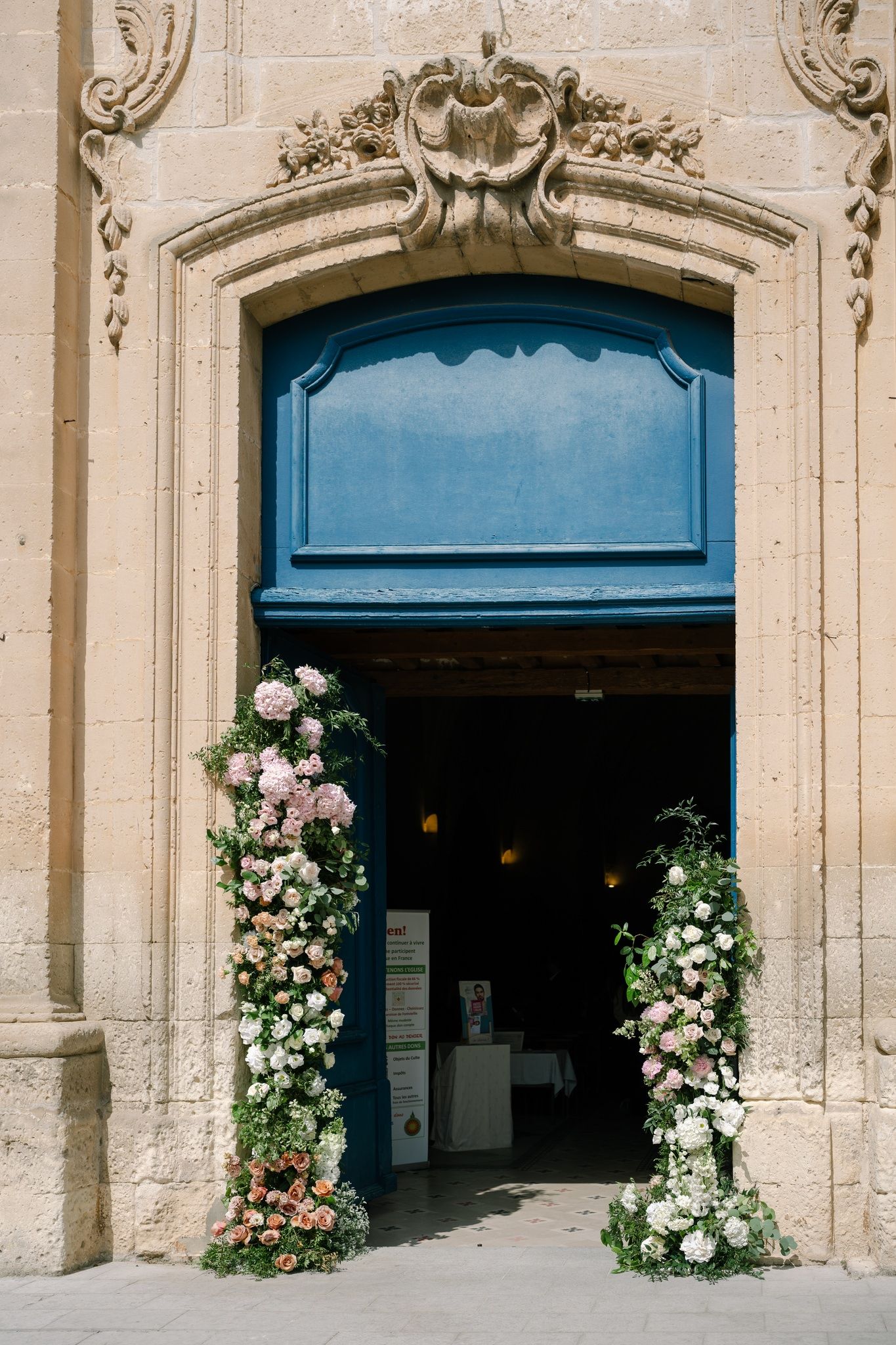 Elegant stone archway entrance decorated with lush white and pink floral arrangements.
