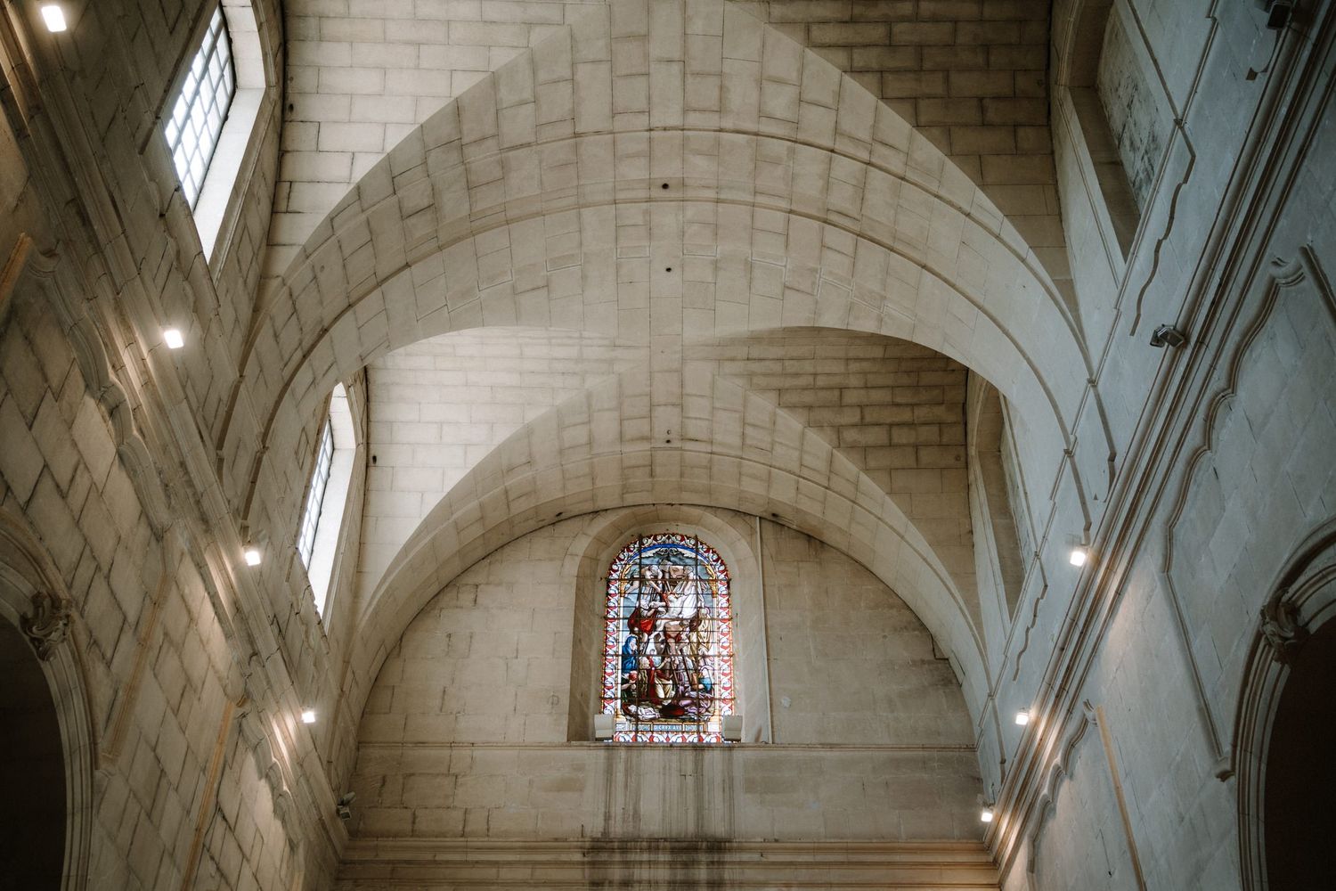 Gothic stone church interior with vaulted ceilings and stained glass windows.