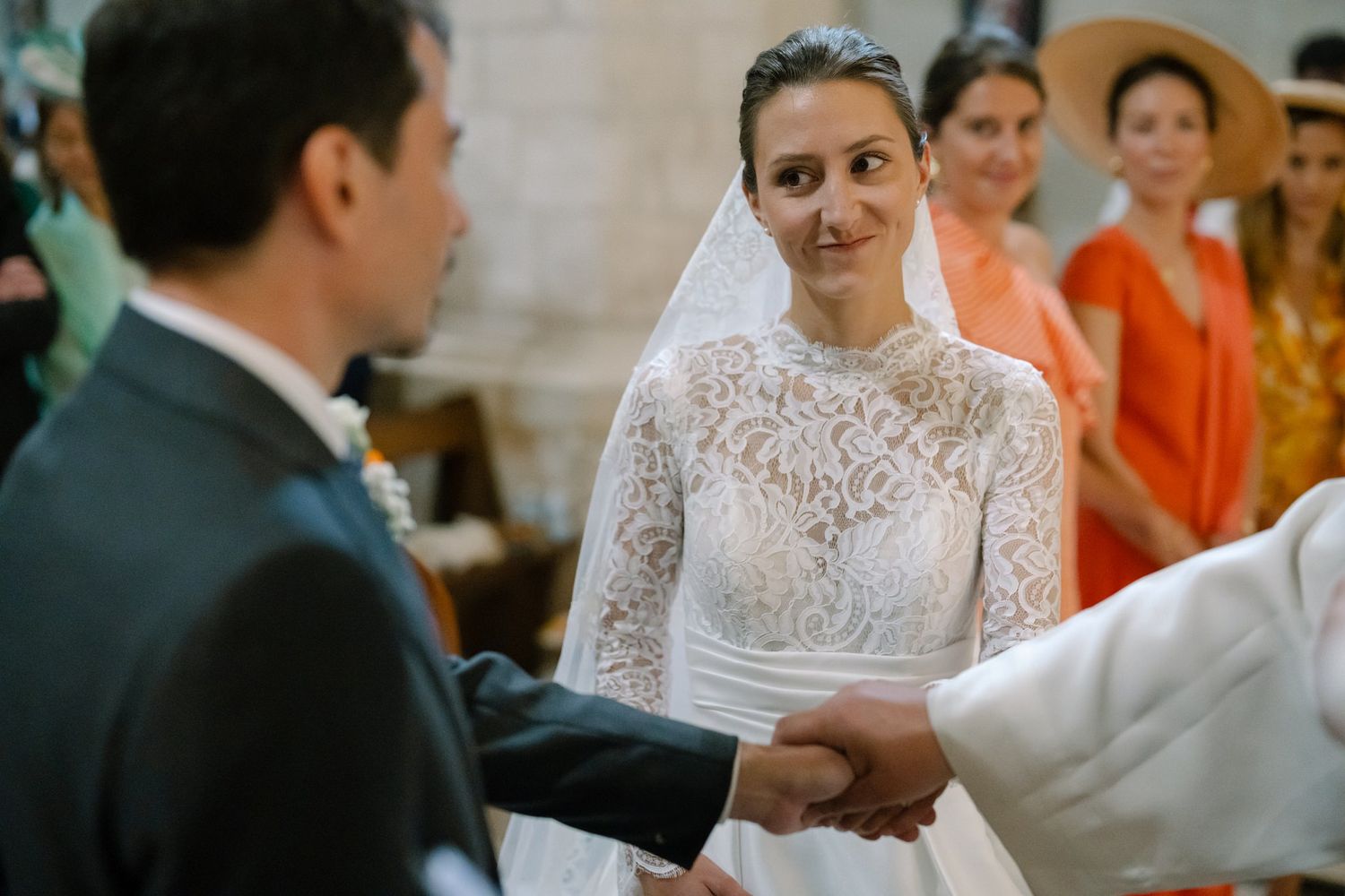 Close-up of wedding ceremony with bride in lace gown exchanging vows.