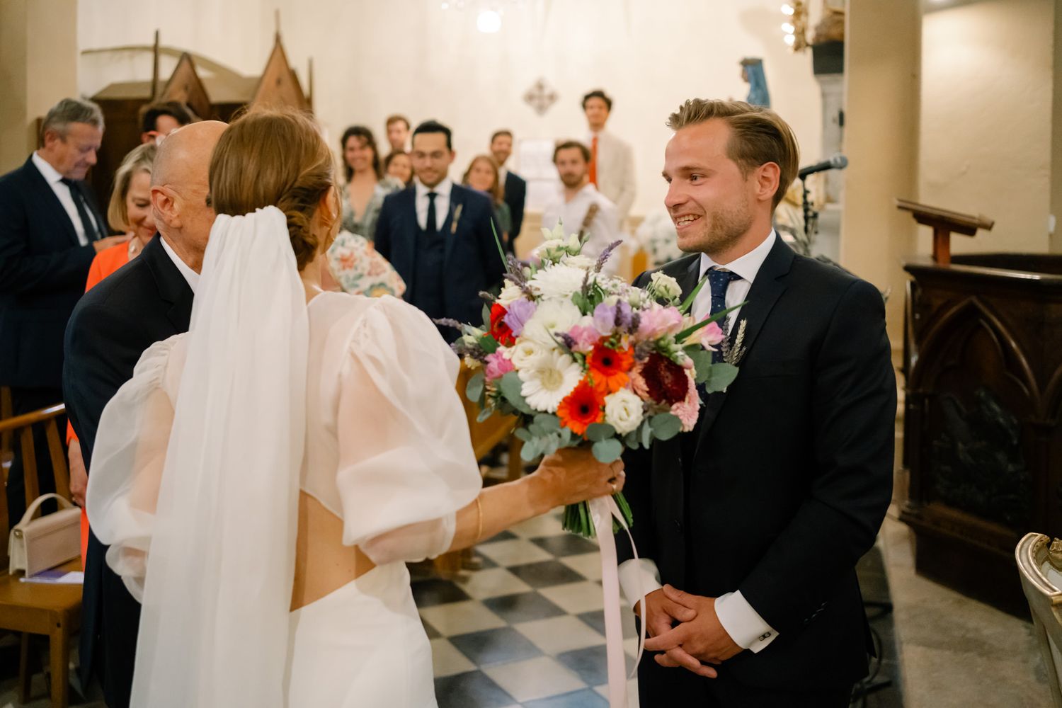 Wedding ceremony in progress inside traditional church with ornate decor.
