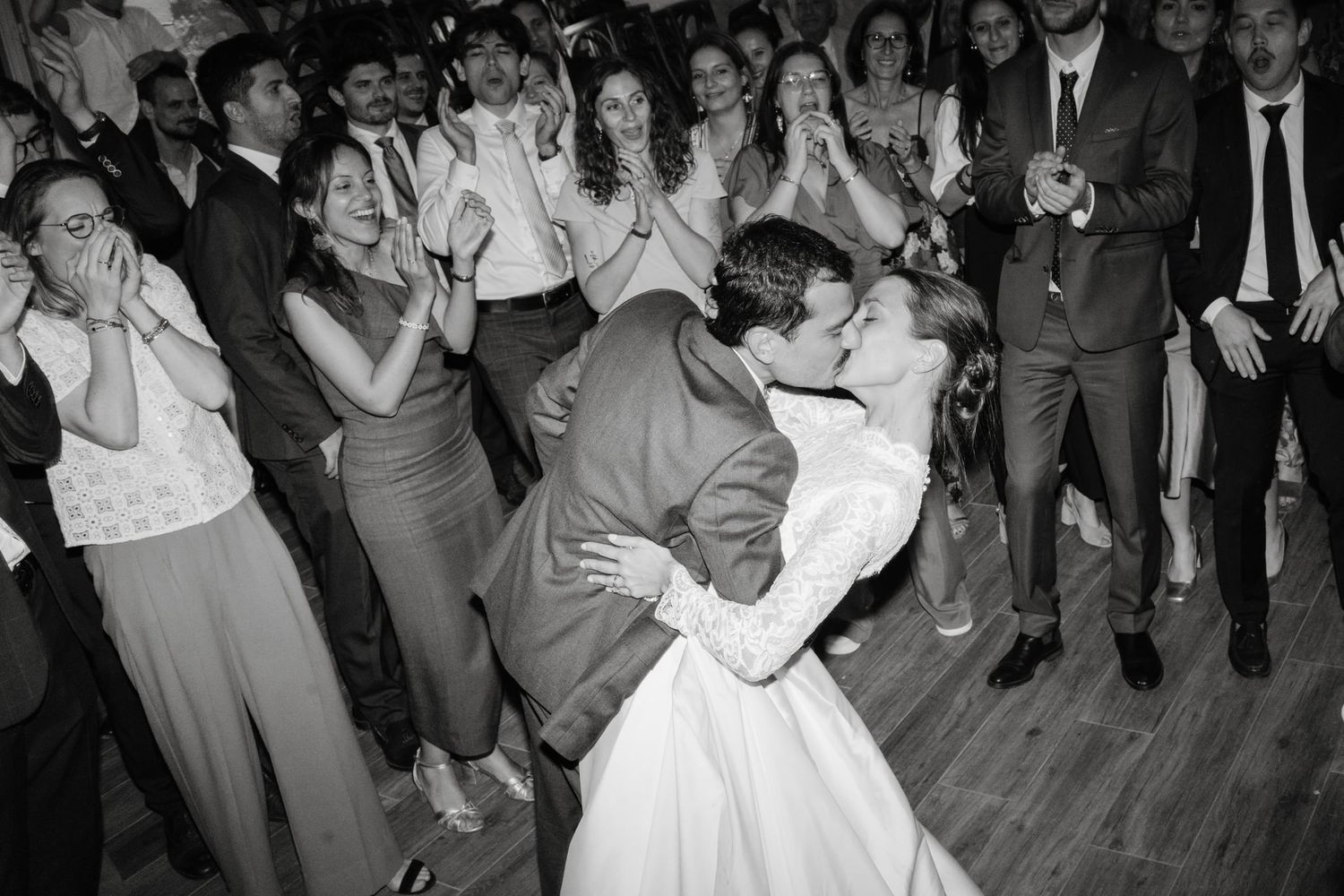 Black and white photo of wedding guests dancing and celebrating on a packed dance floor.