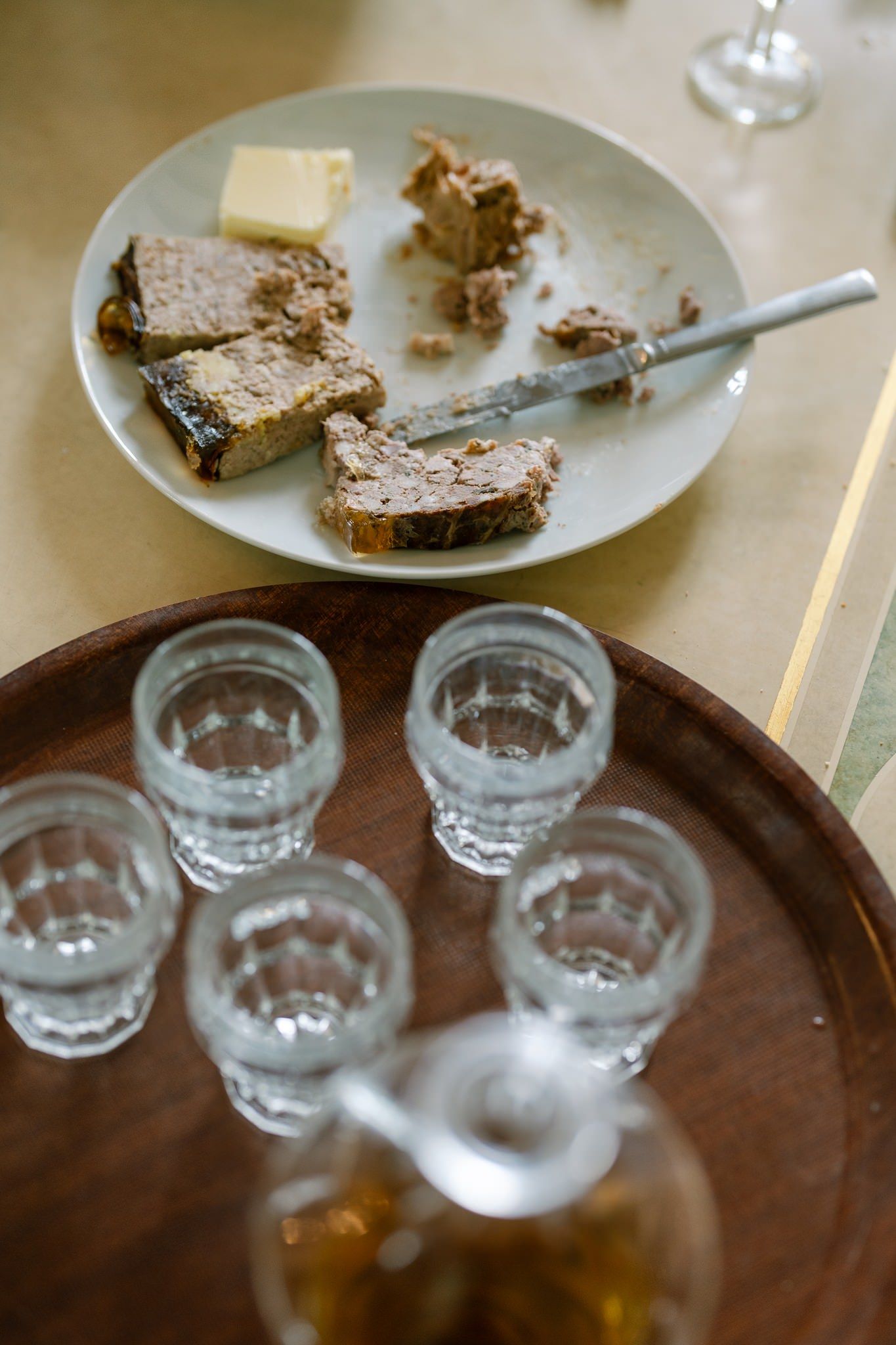 Wooden tray with glasses and plates of bread or cake on a rustic table setting.