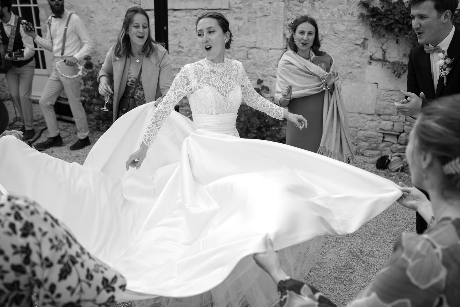 Wedding dress flowing dramatically during outdoor celebration.
