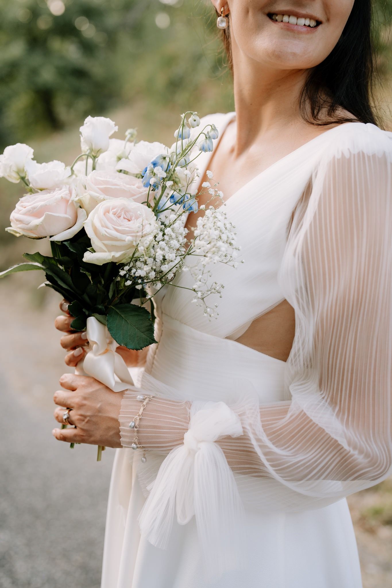 Delicate details of white wedding dresses and rose bouquets held by wedding party members.